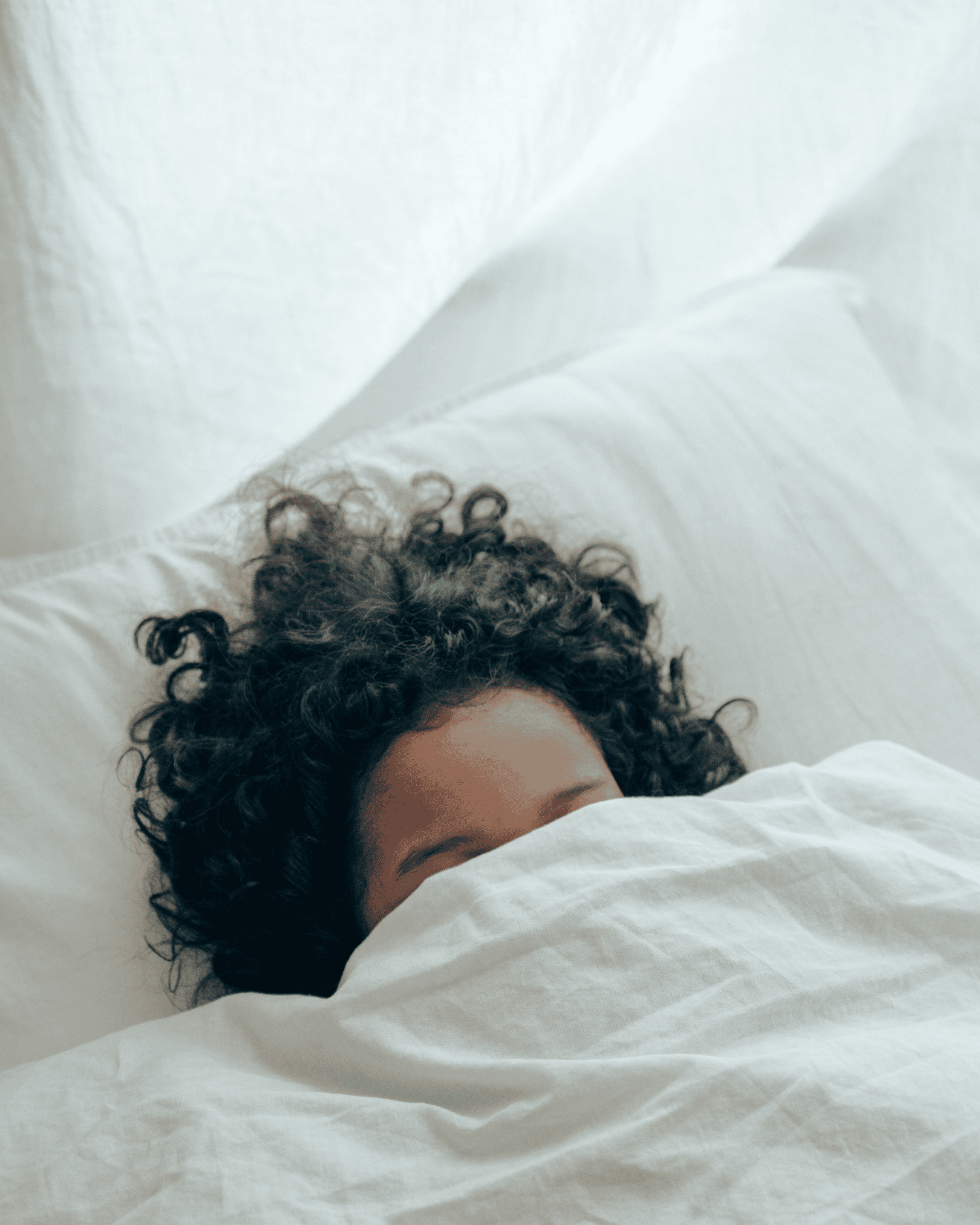 Vrouw slaapt rustig onder een dun linnen laken — ademend beddengoed helpt tegen slecht slapen door warmte