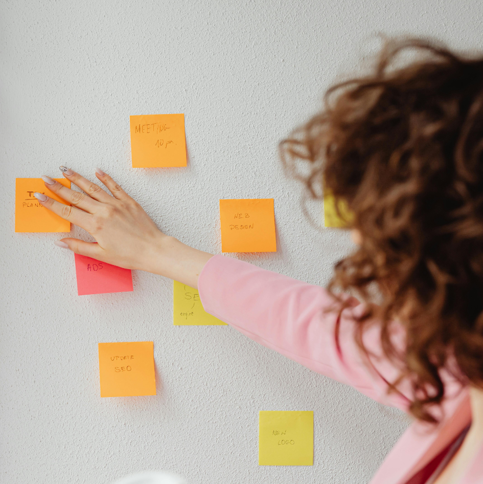 Vrouw met ADHD ordent kleurrijke post-its op muur om overzicht te creëren in druk hoofd
